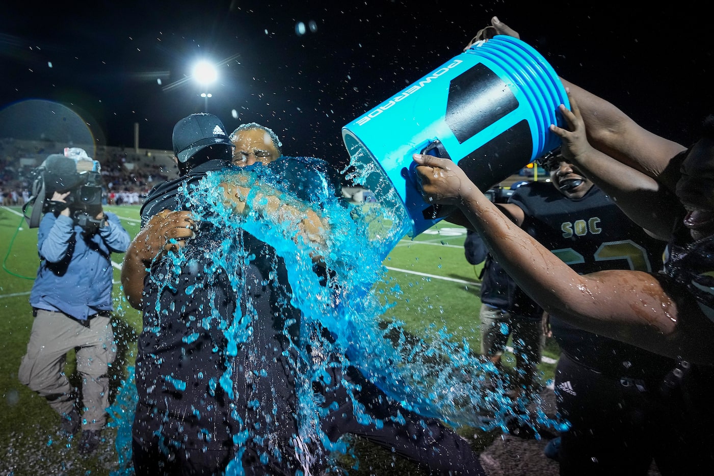 South Oak Cliff head coach Jason Todd is doused by his players as he hugs assistant coach...