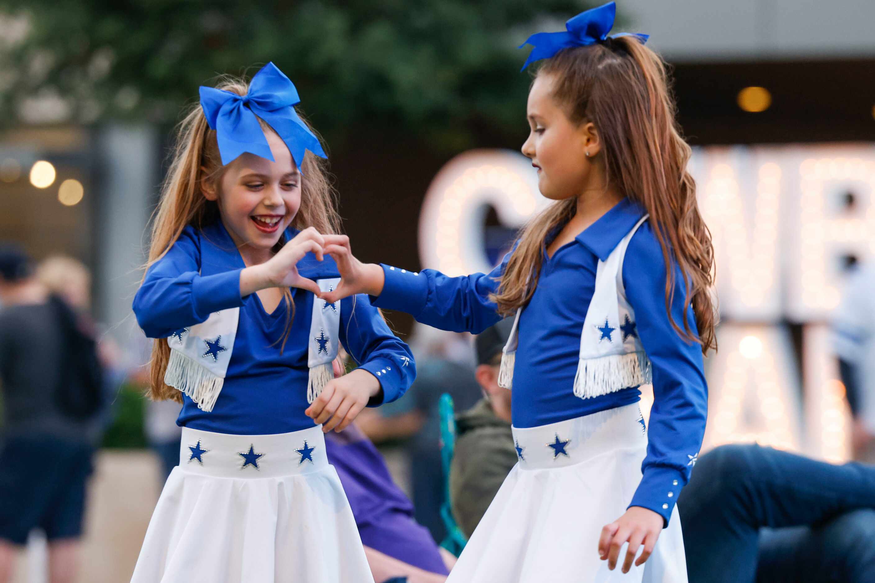 Hannah Paulek, 9, (left) gestures a heart sign with her friend Amelia Purdue, 9, as they...