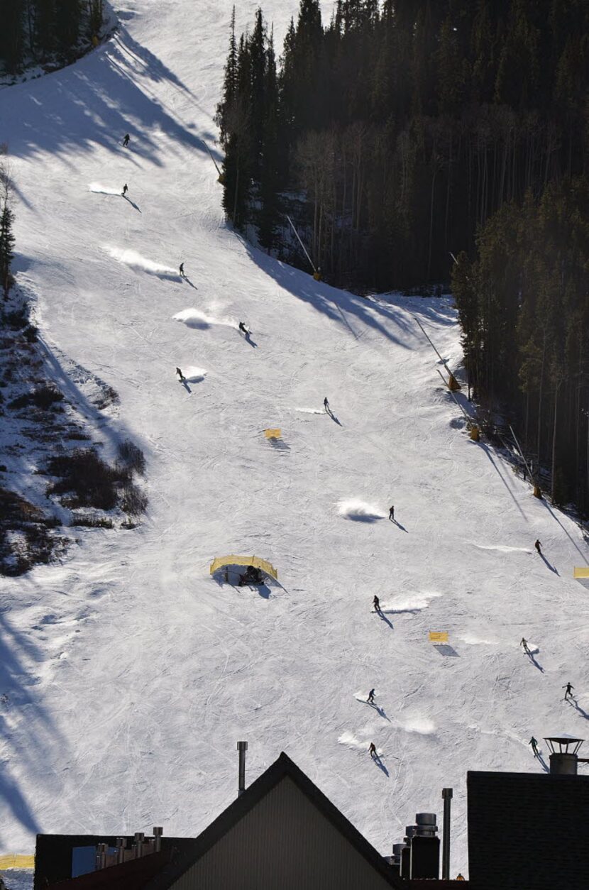 Skiers and riders stir up the snow on a sunlit River Run at the ski resort in  Keystone,...