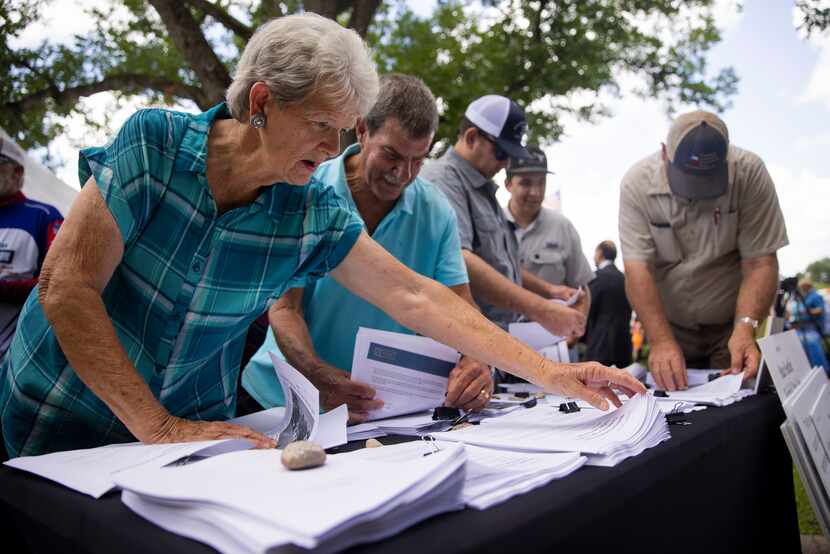 Loretta Anderson of Fairfield grabs documents shown during a news conference by Todd...