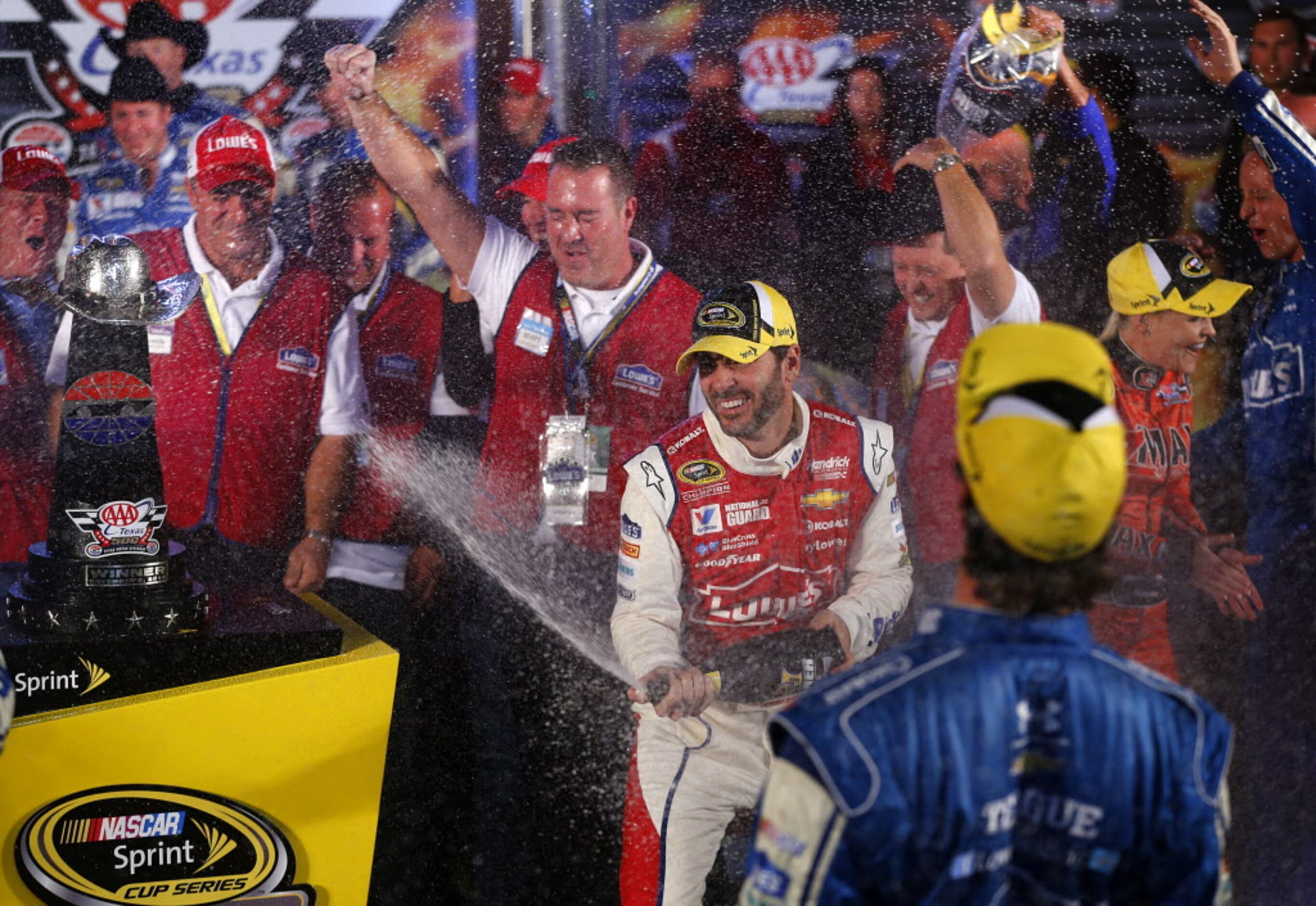 Sprint Cup Series driver Jimmie Johnson sprays champagne on his crew as he celebrates his...