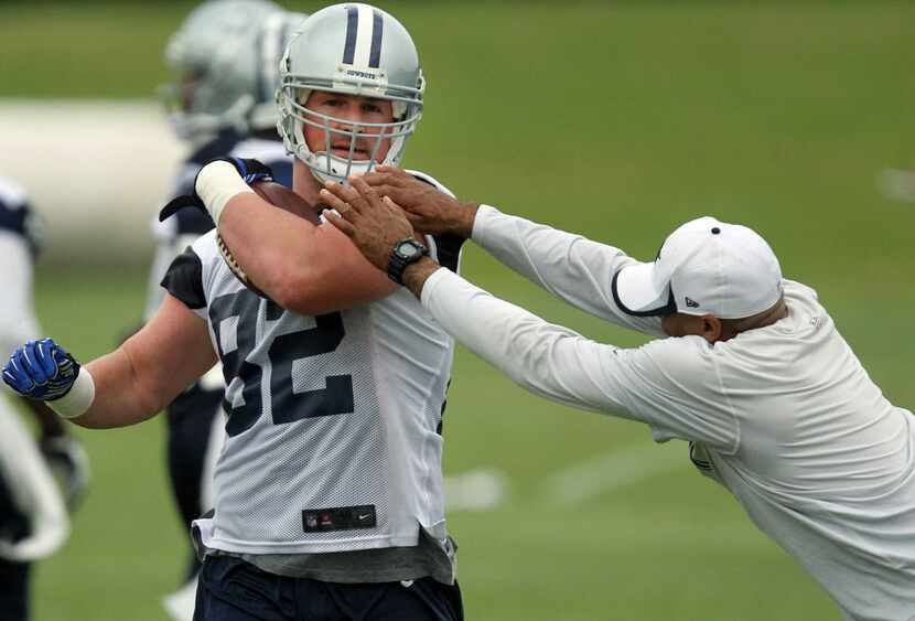 Even a coach tries to strip the ball from tight end Jason Witten (82) as he runs after the...
