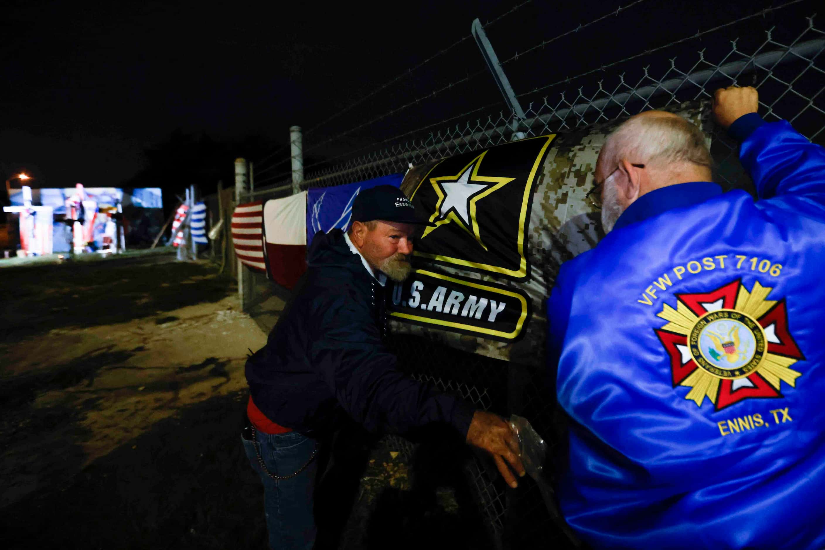 David, 59, and Glenn Coleman, 60, put up a U.S Army flag along the fence line of the Dallas...