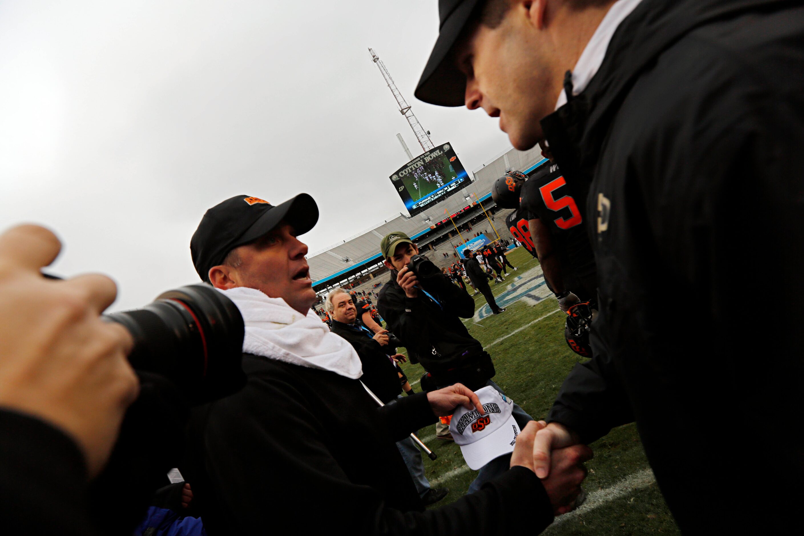 Oklahoma State Cowboys head coach Mike Gundy (left) shakes hands with Purdue Boilermakers...