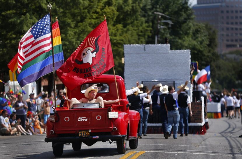 A 'naked' cowboy rides in the back of an old Ford pickup sponsored by the Round-Up Saloon...