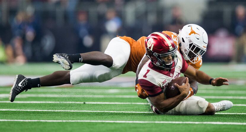 Texas Longhorns linebacker Gary Johnson (33) tackles Oklahoma Sooners quarterback Kyler...