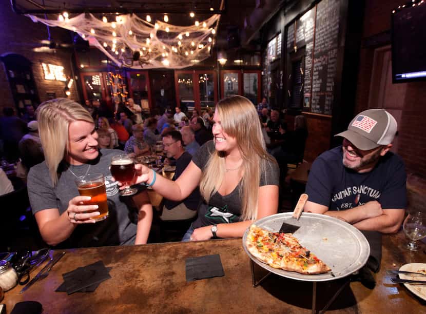 Mindy Bray, left, Cosmo Underwood, and Stace Carpenter enjoy some beer and pizza at Cadillac...