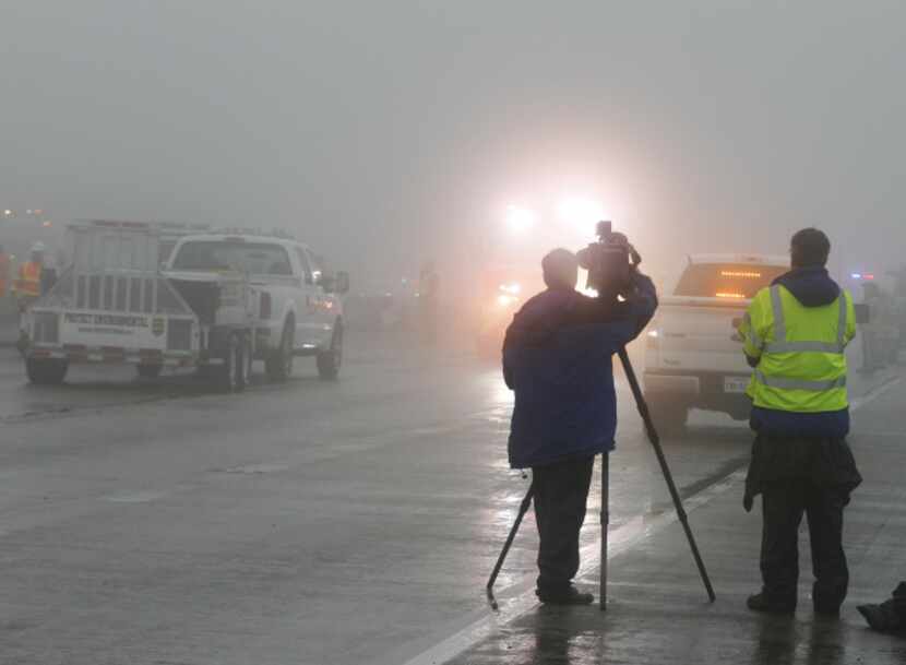 A local TV reporter and photographer work in the fog after an accident early Friday morning...