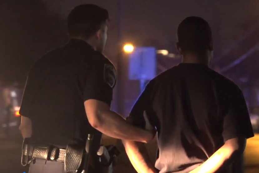 A Farmers Branch police officer leads a suspect after he was arrested during a standoff...