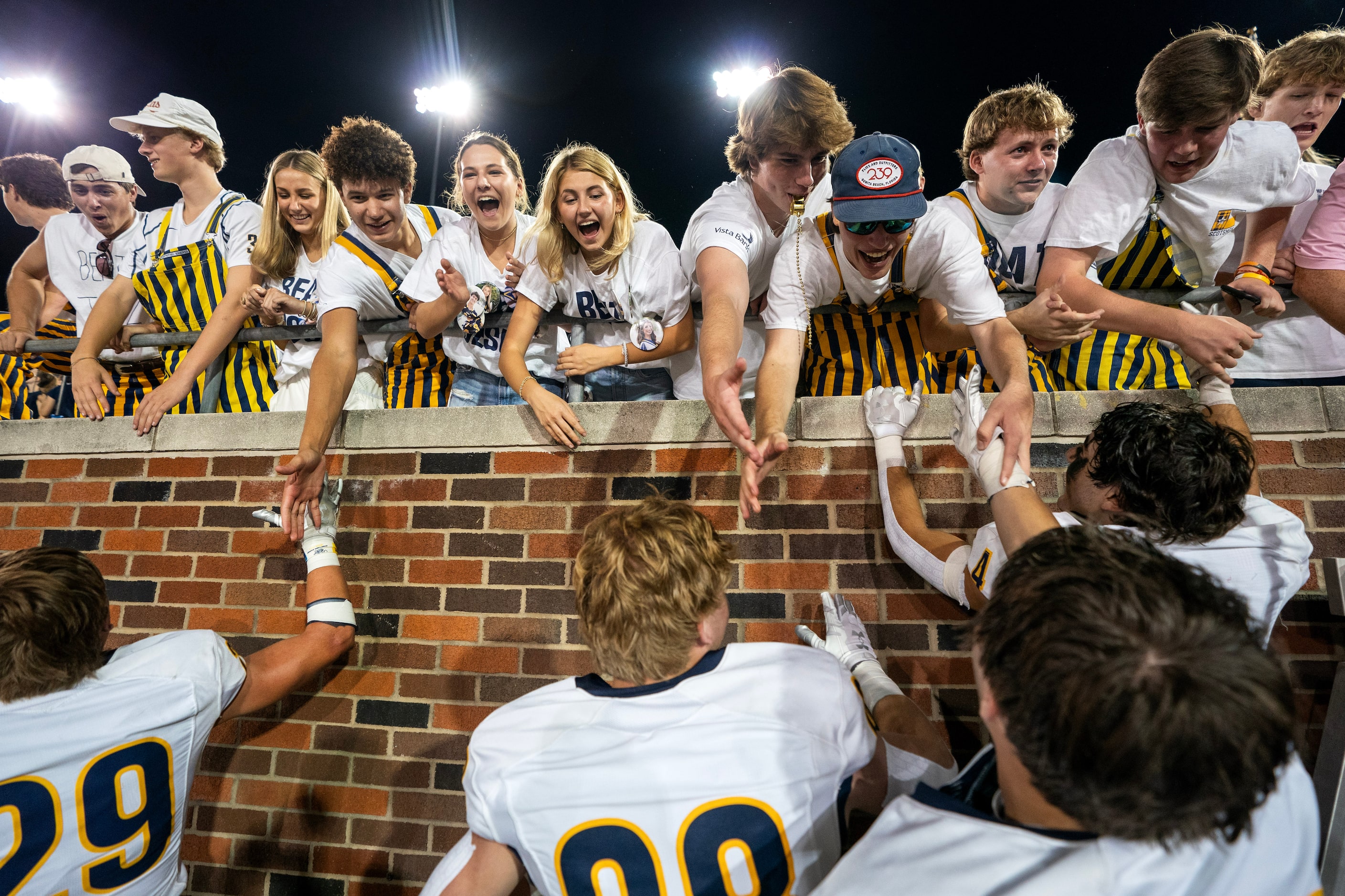 Highland Park Scots players celebrate with fans after their 15-13 win over Jesuit in a high...