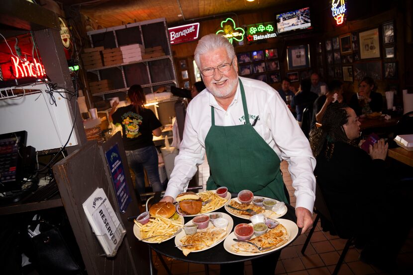 Randy Ford, president and owner of J.Gilligan's Bar and Grill, carries food to customers at...