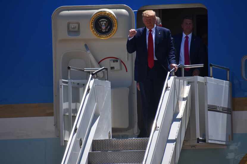 President Donald Trump pumps his fist as he steps off Air Force One upon arrival in Dallas...