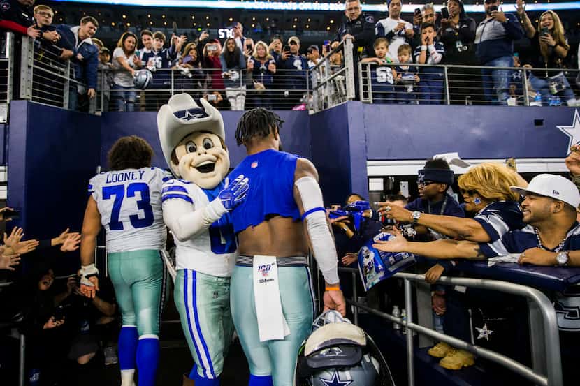 Dallas Cowboys mascot Rowdy pats running back Ezekiel Elliott (21) on the back as he and...