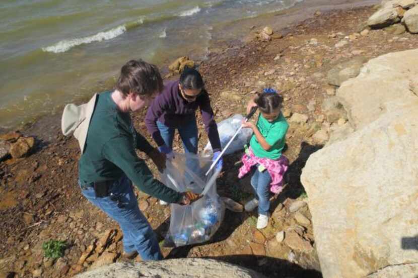 Volunteers gather trash near a lake. Irving is recruiting volunteers for its annual...