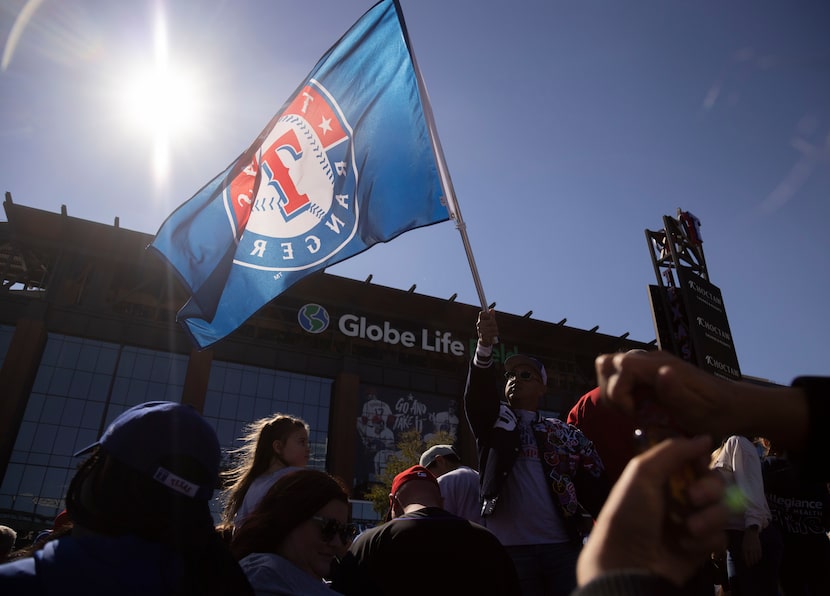 Un aficionado ondea una bandera de los Texas Rangers afuera del Globe Life Field en...