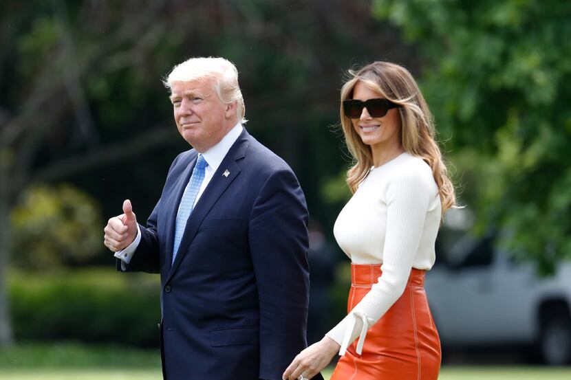 President Donald Trump, with first lady Melania Trump, gives a thumbs-up as they walk across...