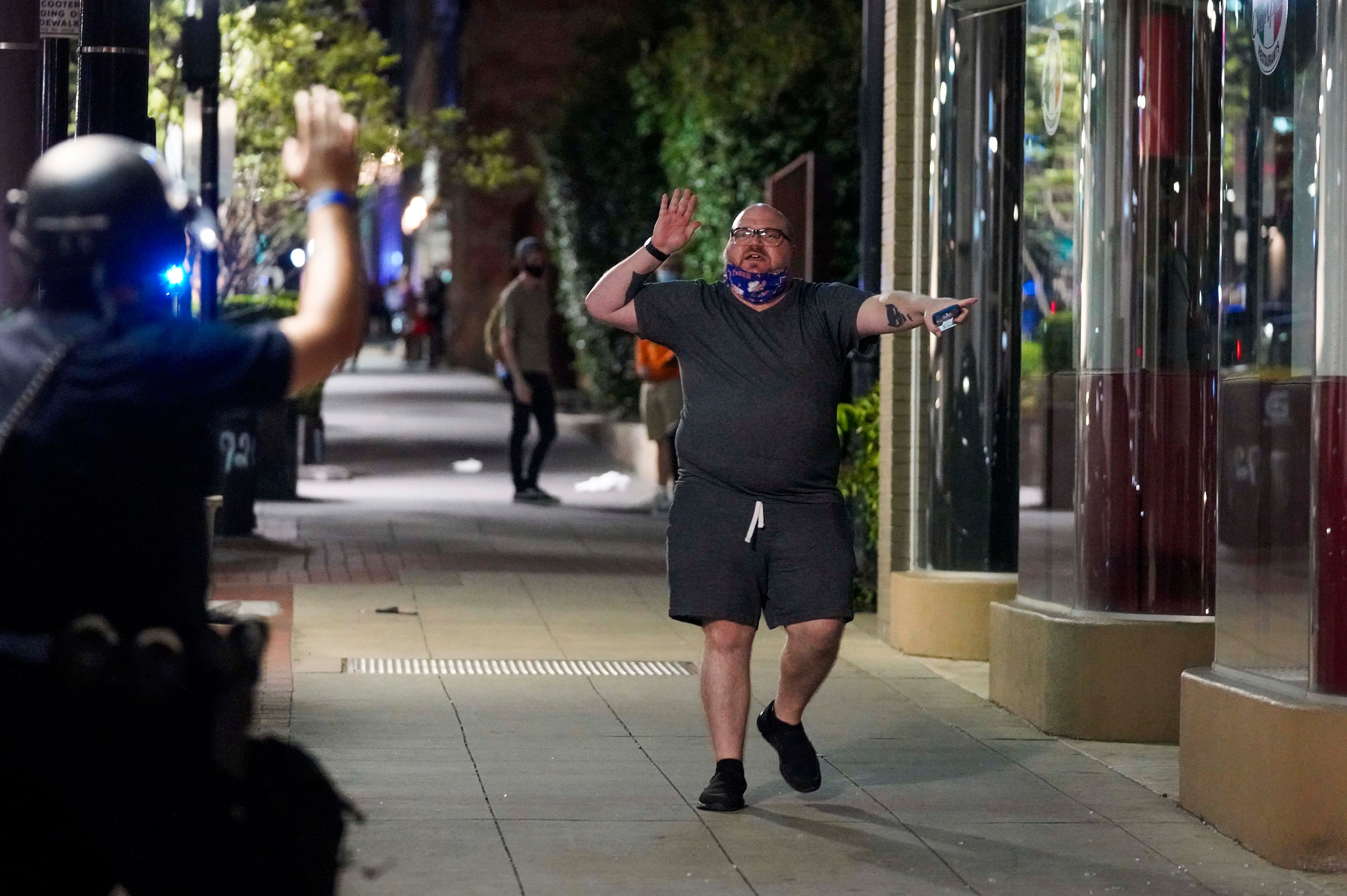 A man motions to police working to clear groups of people from downtown streets that he is...