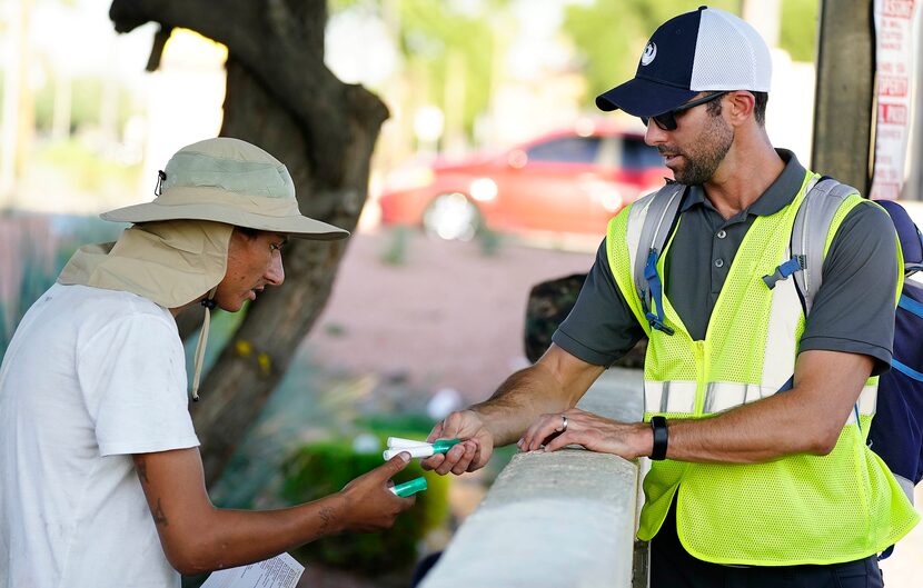 Director of the Office or Heat Response and Mitigations David Hondula hands out sun tan...