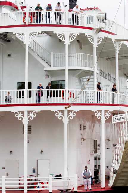 Passengers aboard the American Duchess watch as the ship prepares to dock on the riverfront...