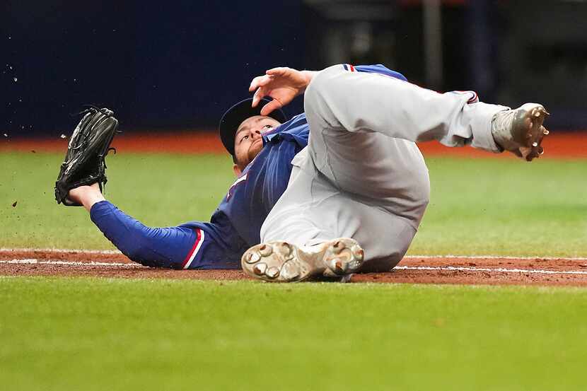 Texas Rangers starting pitcher Jordan Montgomery (52) tumbles as he makes a diving catch on...