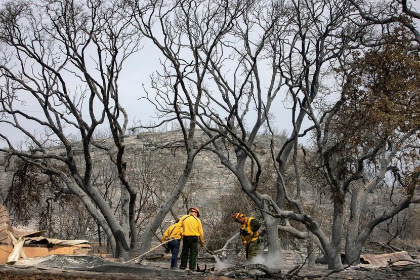 Firefighters soaked the smoldering ground along Possum Kingdom Lake in Graford, Texas, on...