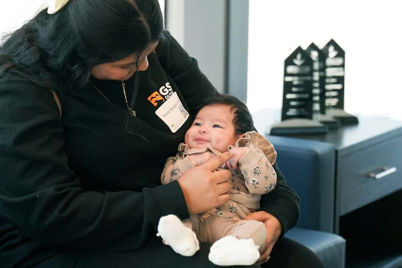 Client Perla Betancourth holds holds her daughter Nahia after a ribbon cutting ceremony at...