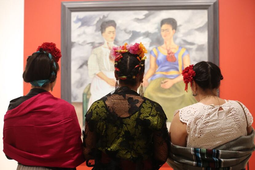 Three Frida Kahlo lookalikes stand in front of the artist's 1939 work, 'The Two Fridas,' at...