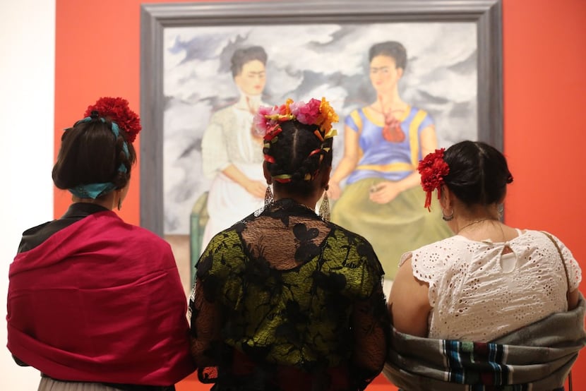 Three Frida Kahlo lookalikes stand in front of the artist's 1939 work, 'The Two Fridas,' at...