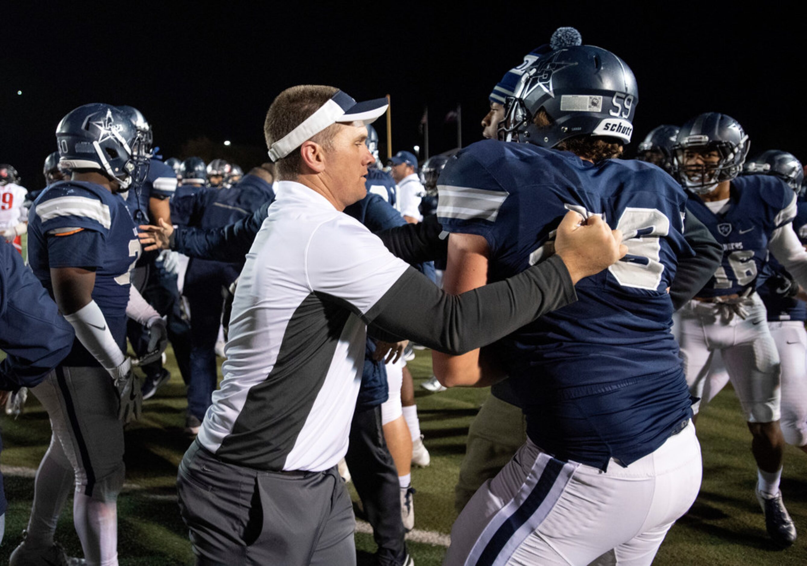 A Frisco Lone Star assistant coach ushers senior offensive lineman Tristan Frizell (59) back...