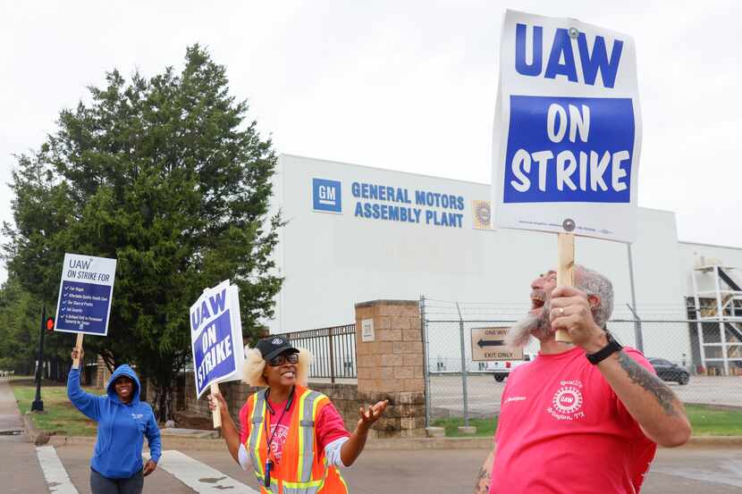 United Auto Workers members engage in a conversation as they strike outside of the General...