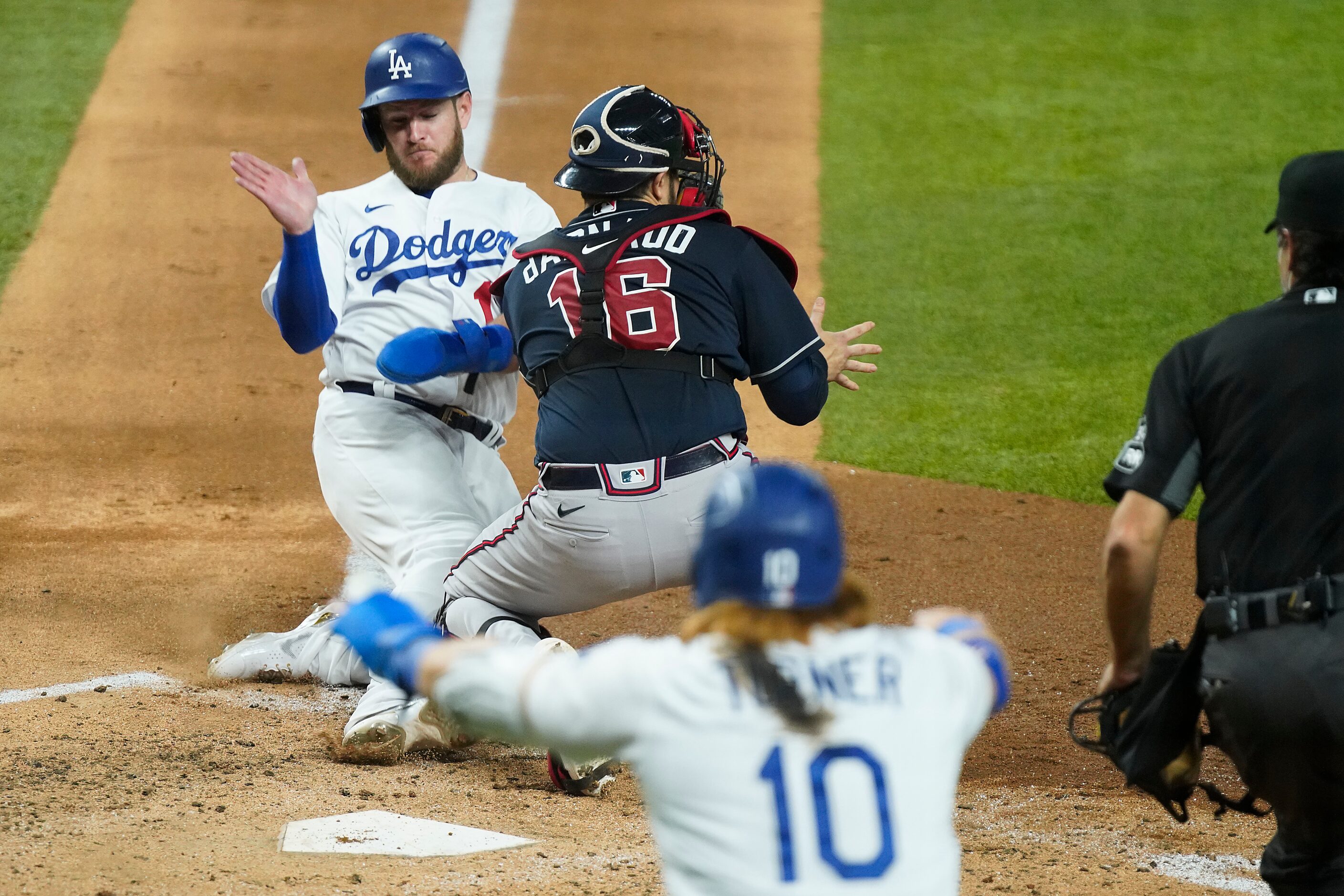 Los Angeles Dodgers first baseman Max Muncy scores past Atlanta Braves catcher Travis...