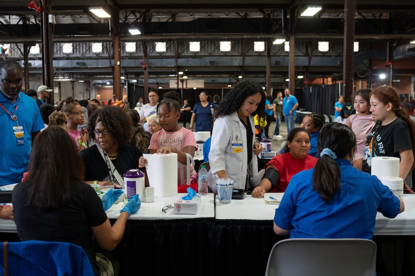 Walmart staff consult with families about vision exams at the Mayor's Back to School Fair at...