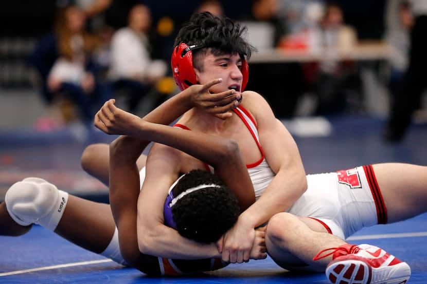 Allen High wrestler Kade Moore (top) gains control of Rockwall's Zach Flowers during their...