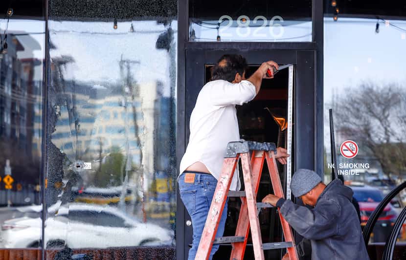 Workers measure the door of Deep Ellum bar Bitter End to replace glass shattered by bullet...