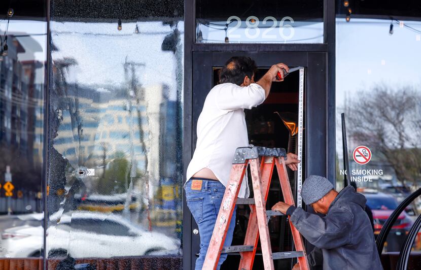Workers measure the door of Deep Ellum bar Bitter End to replace glass shattered by bullet...