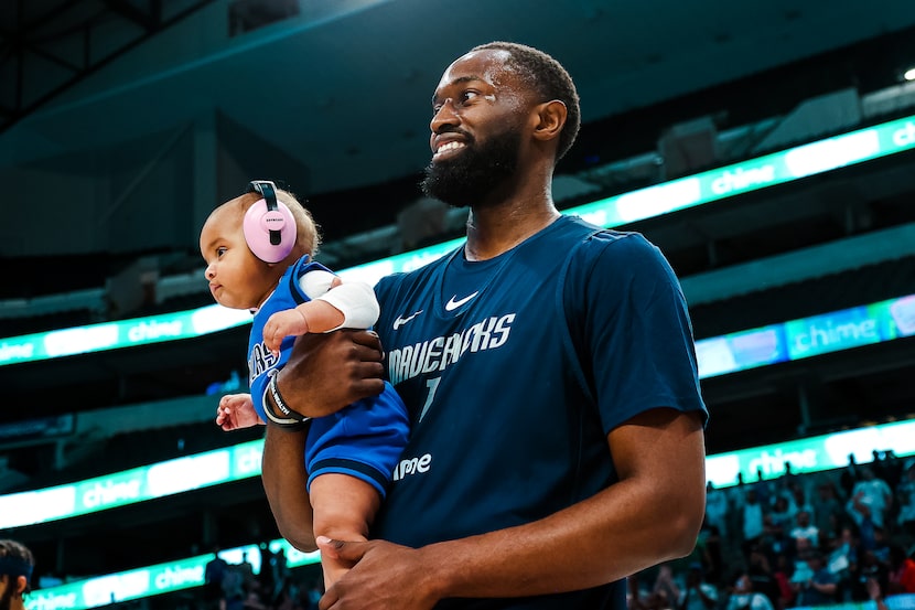 Mavericks guard Theo Pinson carries his daughter, Alana, onto the court during the team's...