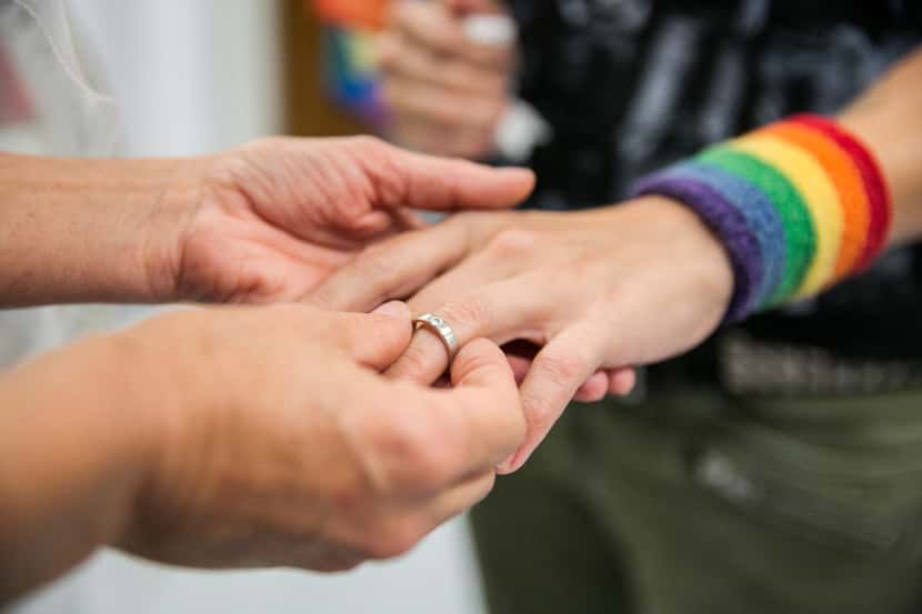 Natalie Novoa has her wedding ring put on by Eddie Daniels, left, as the couple marry during...