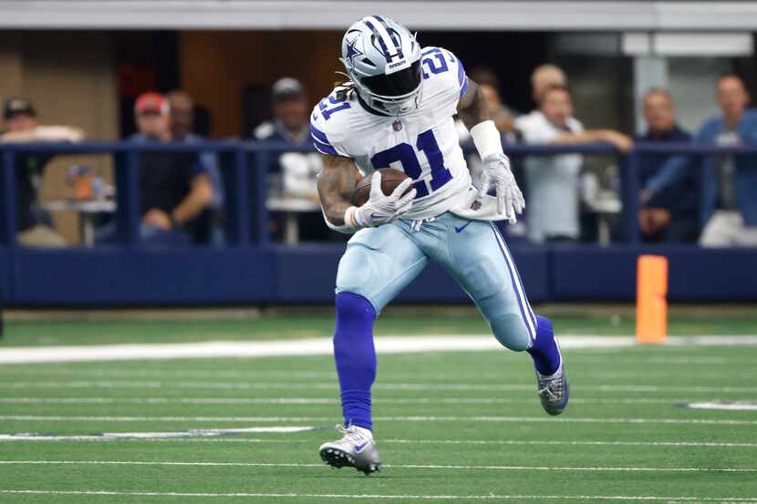 El corredor de los Cowboys de Dallas, Ezekiel Elliott (21), acarrea el balón en el juego...