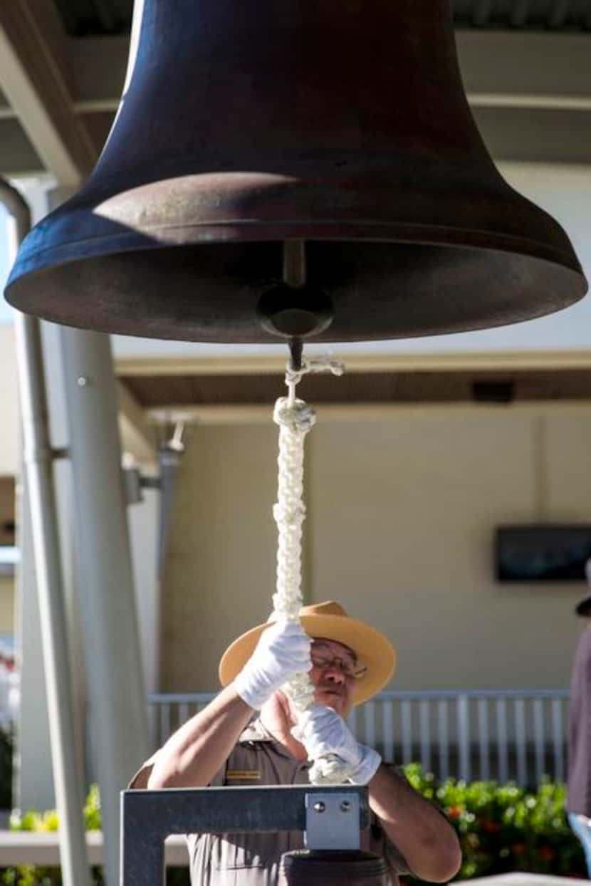 National Park Service Ranger Christopher Chang rings the bell of the Arizona at the ceremony. 