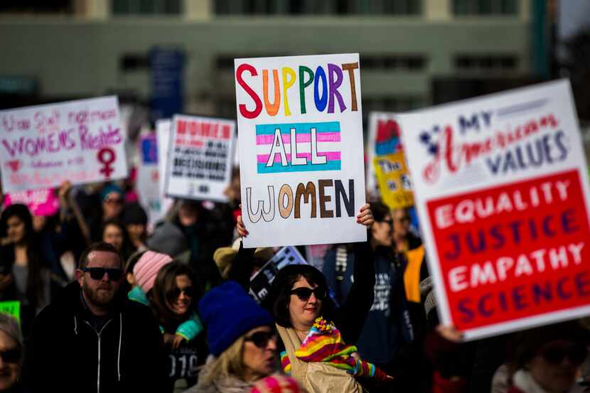 Demonstrators hold up signs during the Dallas Women's March on Sunday, January 20, 2019, in...