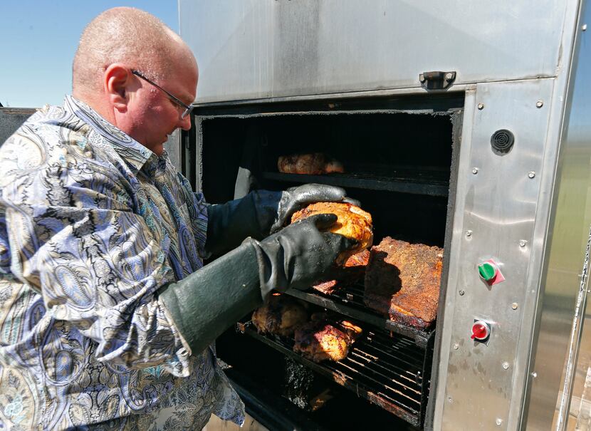 Ricky Kleibrink moves a chicken on racks in his outdoor oven.