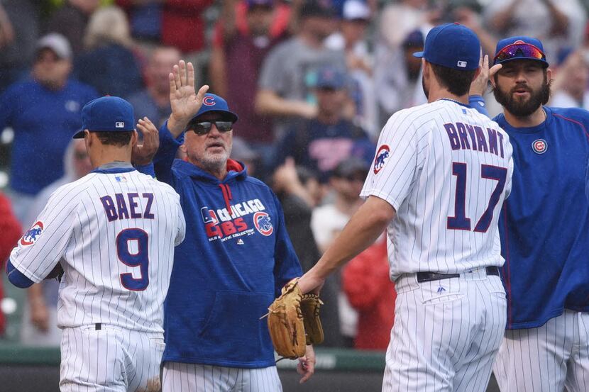 Chicago Cubs manager Joe Maddon, middle, congratulates team members including third baseman...