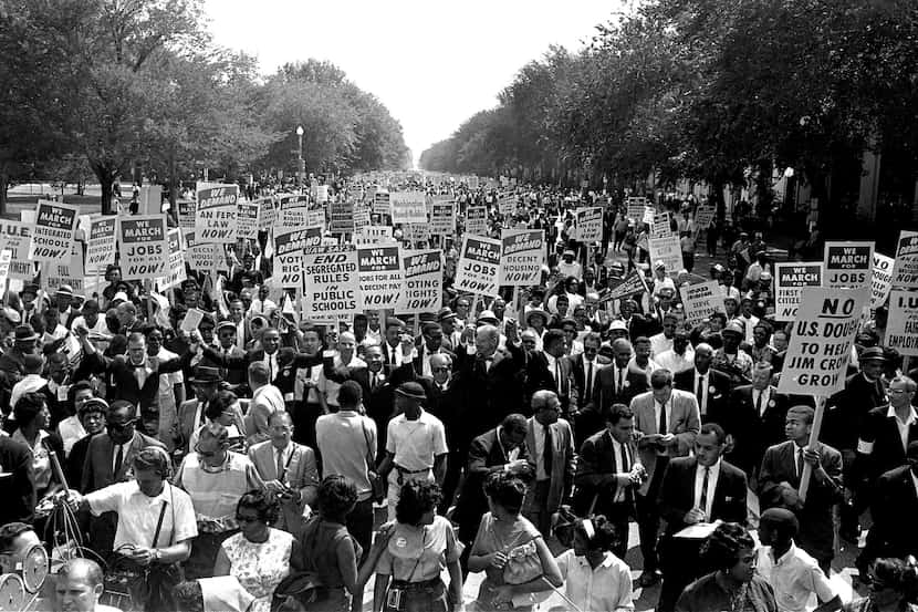 The Rev. Martin Luther King Jr. (center left with arms raised) marches along Constitution...