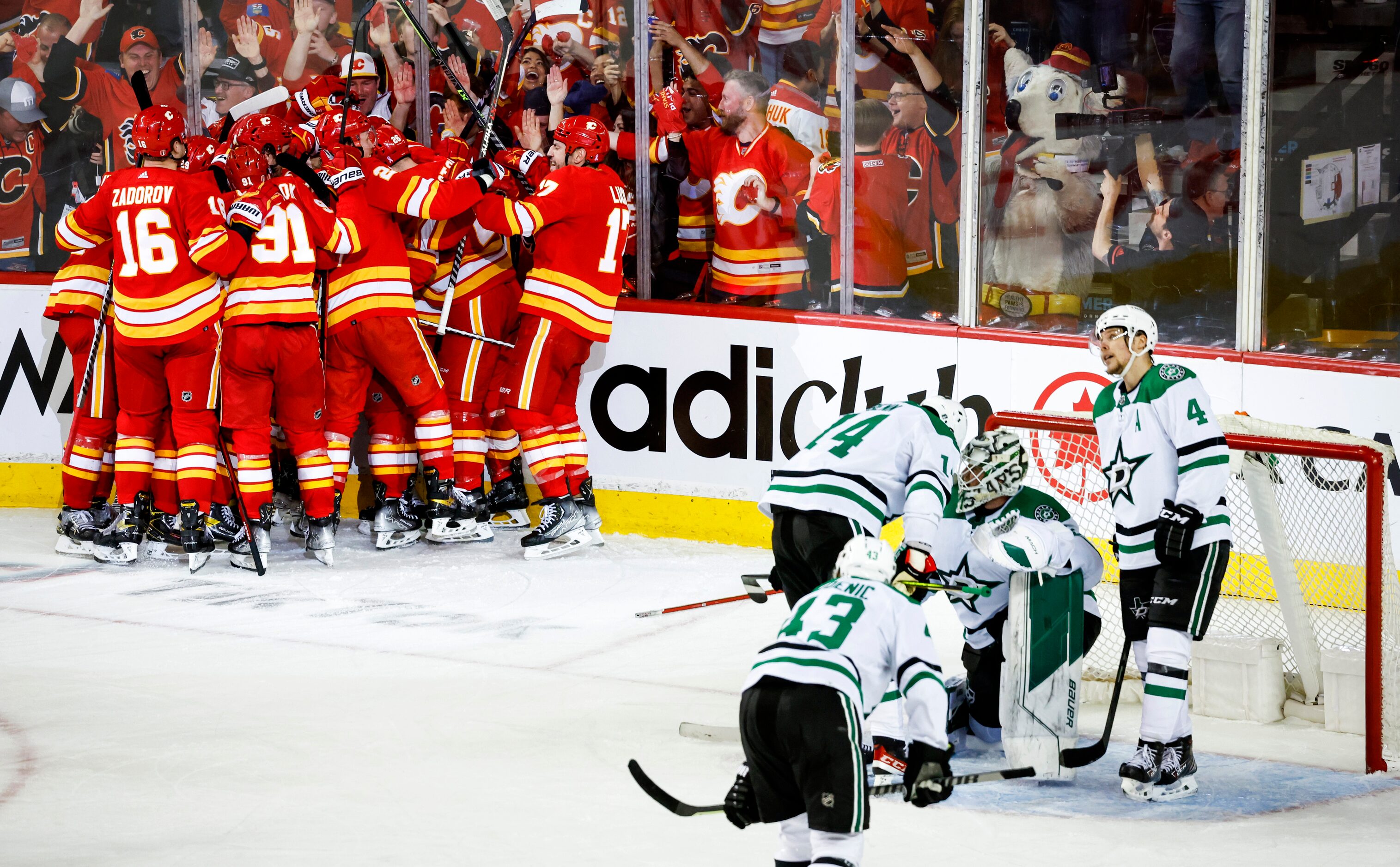 Dallas Stars goalie Jake Oettinger, second from right, is consoled by teammates as Calgary...