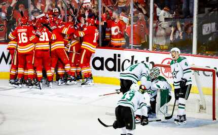 Dallas Stars goalie Jake Oettinger, second from right, is consoled by teammates as Calgary...