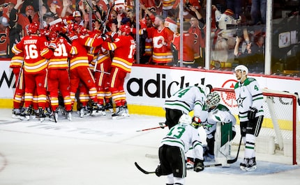 Dallas Stars goalie Jake Oettinger, second from right, is consoled by teammates as Calgary...