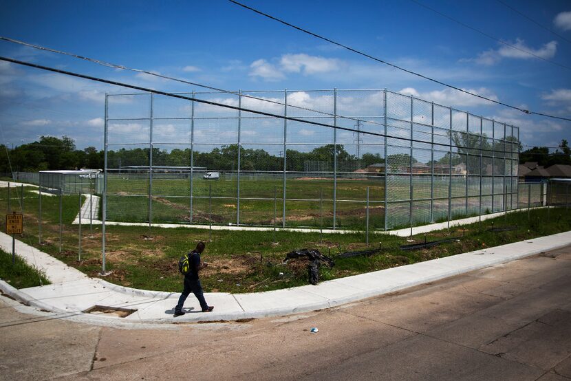 A man walks past a vacant lot that is being turned into a baseball field at at the corner of...