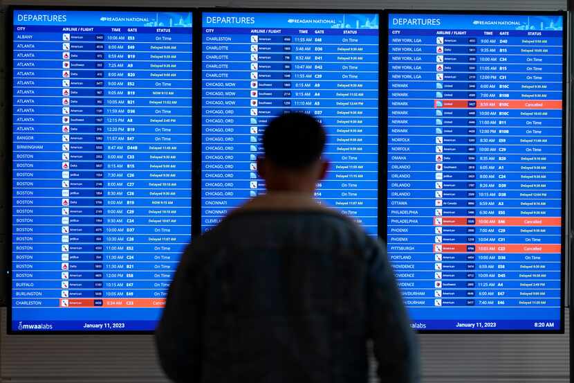 A traveler looks at a flight board with delays and cancellations at Ronald Reagan Washington...