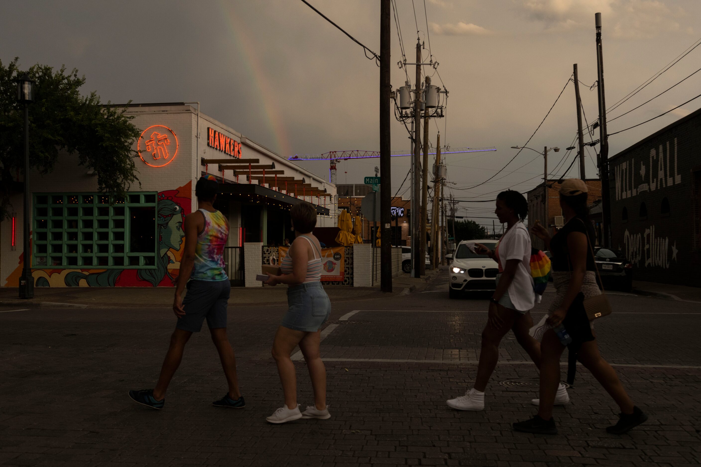 People turn to look at a rainbow as they cross an intersection in the Deep Ellum district of...