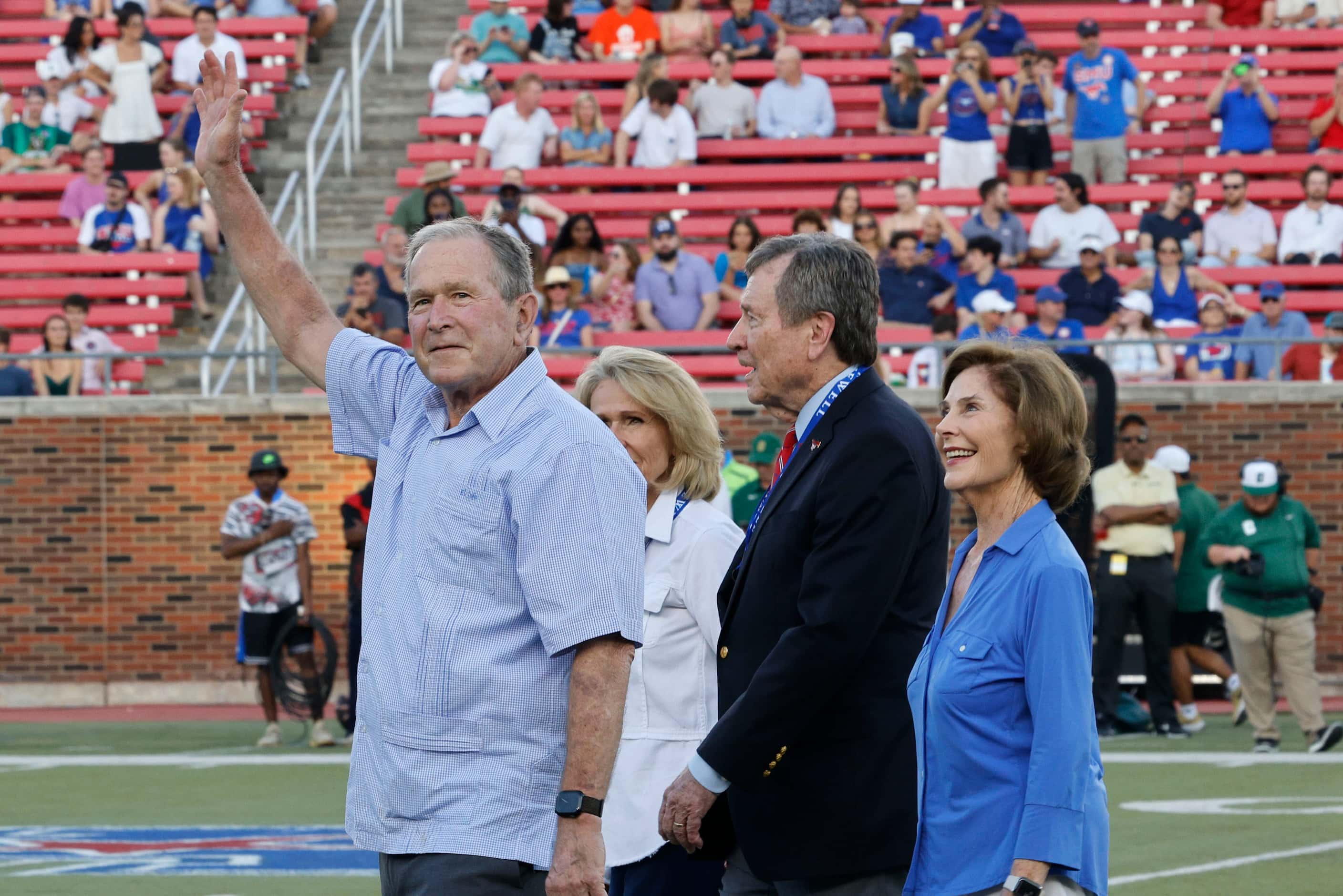 Former President George W. Bush, left, waves with his wife former first lady Laura Bush,...
